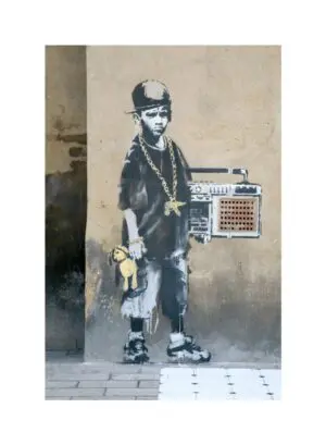 This image shows artwork Dalston by Banksy. The image depicts a wall with black and white graffiti. The graffiti depicts a boy holding a ghetto blaster in one hand and a teddy bear in the other. The boombox is placed over a wall vent and there is a dance mat stencilled onto the floor below.