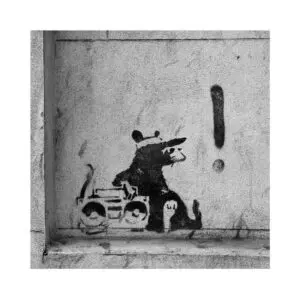 This image is a photograph of a graffiti by Banksy. The picture is a Gangster style mouse wearing sunglasses with a cap laying by a boombox, and next to it there is a exclamation point on a wall in Moorfields.
